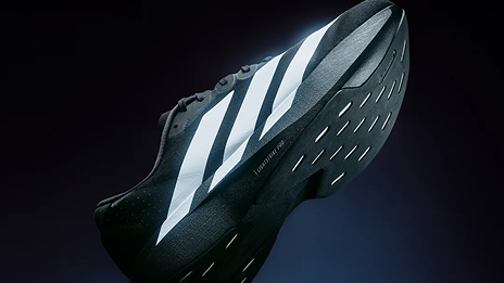 Zapatilla negra de deporte con tres rayas blancas.